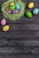 Fototapeta na wymiar Multi-colored easter eggs in a nest on a wooden background