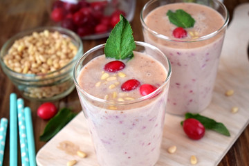 Protein cocktail for healthy nutrition decorated with cranberries, mint and pine kernel nuts in a glass