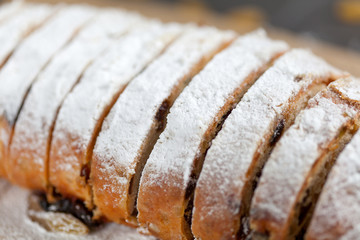 freshly baked cake with sweets, raisins and candied fruits, sprinkled with powdered sugar on a gray table