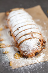freshly baked cake with sweets, raisins and candied fruits, sprinkled with powdered sugar on a gray table