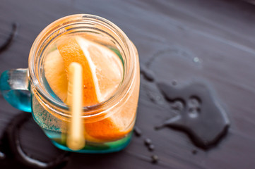 water with orange and lemon in a glass jar on a dark background. concept vitamins and healthy food