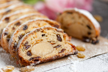 freshly baked cake with sweets, raisins and candied fruits, sprinkled with powdered sugar on a gray table with pink tulips