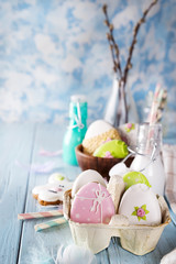 Easter cookies egg in the paper box with milk in glass on wood background