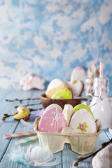 Easter cookies egg in the paper box with milk in glass on wood background