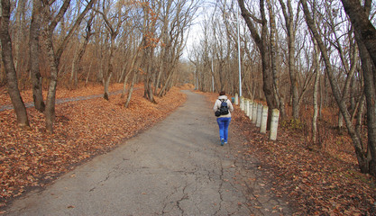 Young woman walking in autumn park close up