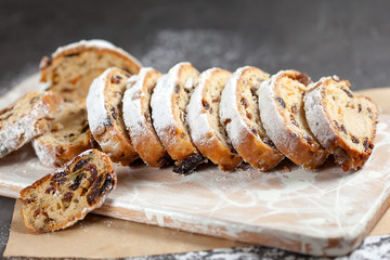 freshly baked cake with sweets, raisins and candied fruits, sprinkled with powdered sugar on a gray table