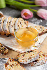 freshly baked cake with sweets, raisins and candied fruits, sprinkled with powdered sugar, a hot drink with apples on a gray table with pink tulips