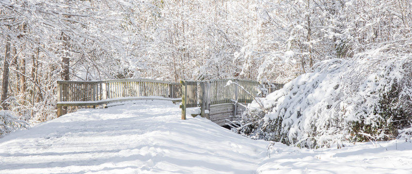 A Wintry Picturesque Landscape Of A Snow Covered Walkway Bridge On A Bright Sunny Afternoon.