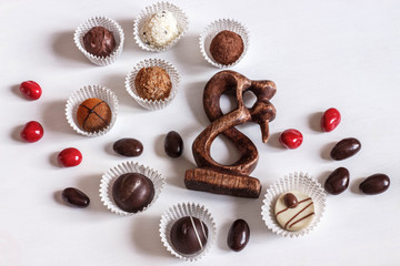 chocolate, nuts and wooden statuette of lovers on a white background