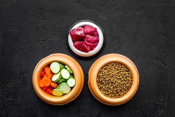 Ingredients for dry pet food. Meat and vegetables zucchini and carrot on black backgroud top view copy space