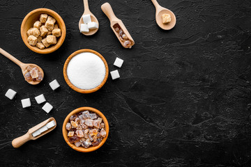 Brown and white sugar in bowls, scoop and spoon. Cane, refind, granulated, cubes, candy. Black background top view copy space