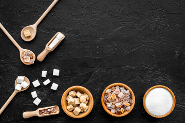 Obraz na płótnie Canvas Brown and white sugar in bowls, scoop and spoon. Cane, refind, granulated, cubes, candy. Black background top view copy space
