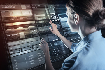 Usual activity. Calm experienced professional programmer standing in front of a futuristic computer...