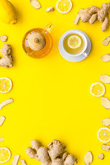 Warming tea with lemon and ginger. Cup, teapot, ginger root on yellow background top view copy space