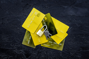 Electronic payments protection. Bank cards near lock and keys on black background top view copy space