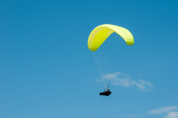 Paraglider flying in the blue sky against the background of clouds. Paragliding in the sky on a sunny day.