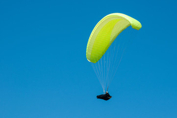 Alone paraglider flying on the background of blue sky. Paragliding in the sky on a sunny day.