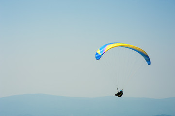 Paraglider flies over a mountain valley on a sunny summer day. Paragliding in the Carpathians in the summer.