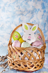 Easter cookies, bunnies and eggs in a basket on light blue background