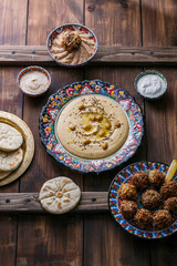 Hummus, chickpea, falafel with tahini, yoghurt and pita in traditional plate