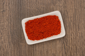 Red pepper powder over wood background