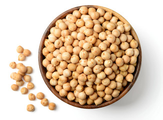 uncooked chickpeas in the wooden bowl, isolated on white, top view