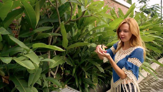 Young caucasian woman releasing olive-backed sunbird from hands in Java, Indonesia