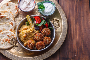 Hummus, falafel, salad in a pan with yoghurt and tahini