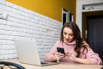 Beautiful girl smile using multiple devices phone and laptop on a table at home