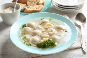 Tasty broth with dumplings on table