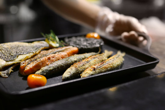 Chef with delicious fried fish platter in restaurant kitchen, closeup