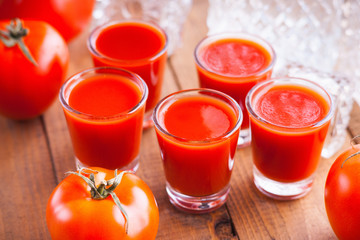 Cold Bloody Mary cocktail shot in glasses and tomatoes