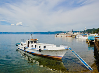 Fototapeta na wymiar Small boat at the pier on Lake Baikal in clear turquoise waters 