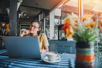 Happiness Asian woman sitting using laptop in a cafe.
Focus on face