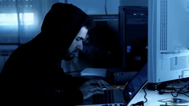  Hacker attacking computer system in a dark office
