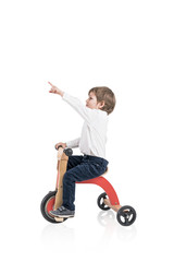Cute boy on a tricycle, showing finger isolated