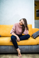 Picture of a tired unkempt woman sitting on he couch at home. Girl watch TV new serial. Sofa relax concept after hard working day. Attentive woman sitting bored on sofa at home