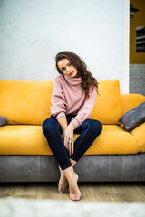 Obraz premium Young woman sitting on her white sofa at home