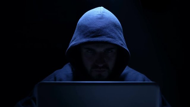 portrait of  Hacker attacking computer system in a dark office