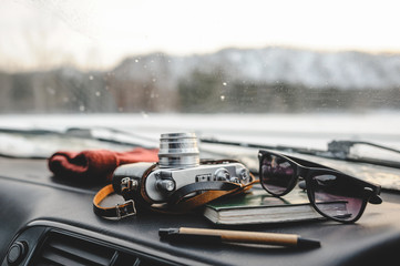 Notebook, glasses and film camera on the dashboard