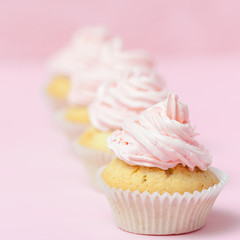 Cupcake decorated with pink buttercream on pastel pink background. Sweet beautiful cake. Square banner, greeting card for birthday, wedding, women's day. Close up photography. Selective focus