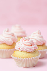 Cupcake decorated with pink buttercream on pastel pink background. Sweet beautiful cake. Vertical banner, greeting card for birthday, wedding, women's day. Close up photography. Selective focus