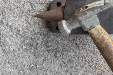 Old small hammer and miniature anvil with concrete background