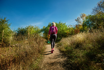 Naklejka premium Back view of sportswoman going to training in autumn park