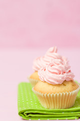 Cupcake decorated with pink buttercream on pastel pink background. Sweet beautiful cake. Vertical banner, greeting card for birthday, wedding, women's day. Close up photography. Selective focus