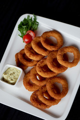 Golden onion rings fried in deep frying. With Sauce on a white plate