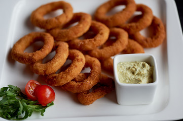 Golden onion rings fried in deep frying. With Sauce on a white plate