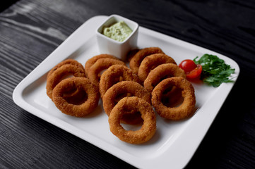 Golden onion rings fried in deep frying. With Sauce on a white plate