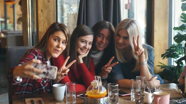 Four beautiful young woman doing selfie in a cafe, best friends girls together having fun