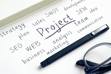 Business success concepts written down on a notepad next to a pen and a pair of glasses.